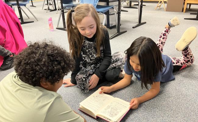 3 students reading a book together