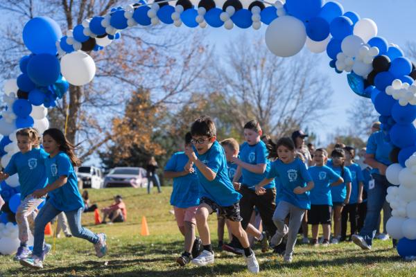 Panther Prowl event with kids running through balloon arch