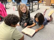 3 students reading a book together